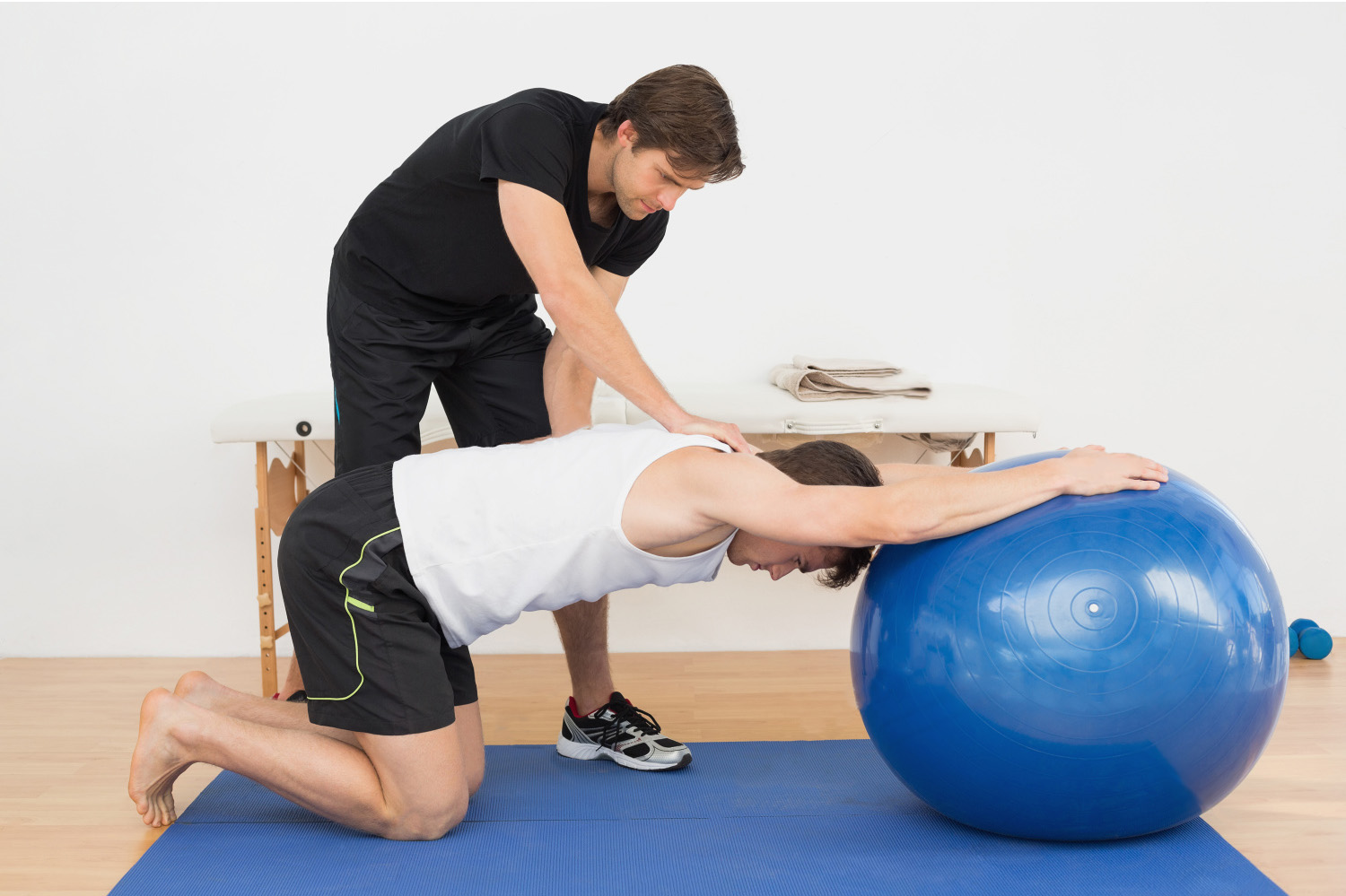 homem fazendo exercícios para fortalecer o quadril com instrutor e bola de pilates