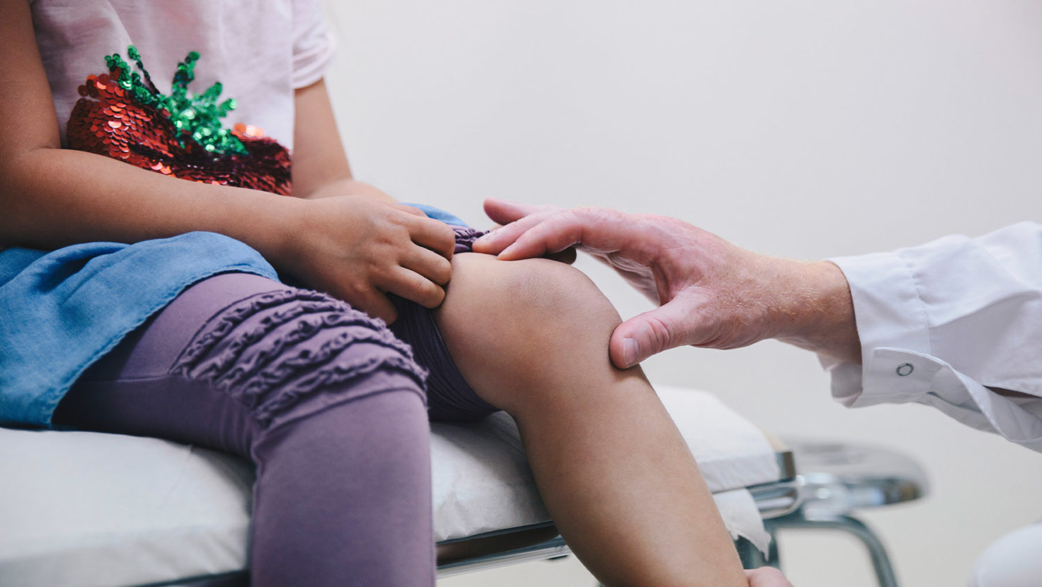 criança examinando o joelho em consultório médico