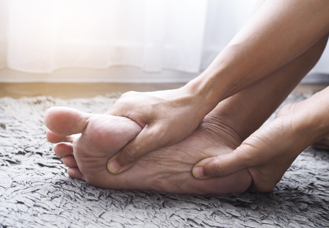 pessoa massageando um dos pés para aliciar a dor no arco do pé
